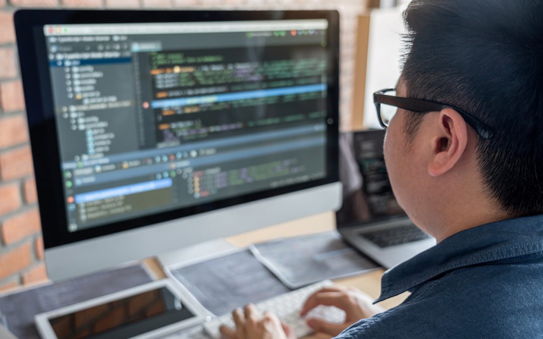 programmer writing code into a web development framework on his computer
